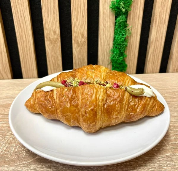 Croissant plněn&yacute; pist&aacute;ciov&yacute;m kr&eacute;mem sypan&yacute; sekan&yacute;mi pist&aacute;ciemi a su&scaron;en&yacute;mi malinami